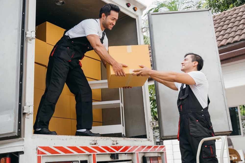 VC Movers crew passing a packed box into the truck on moving day